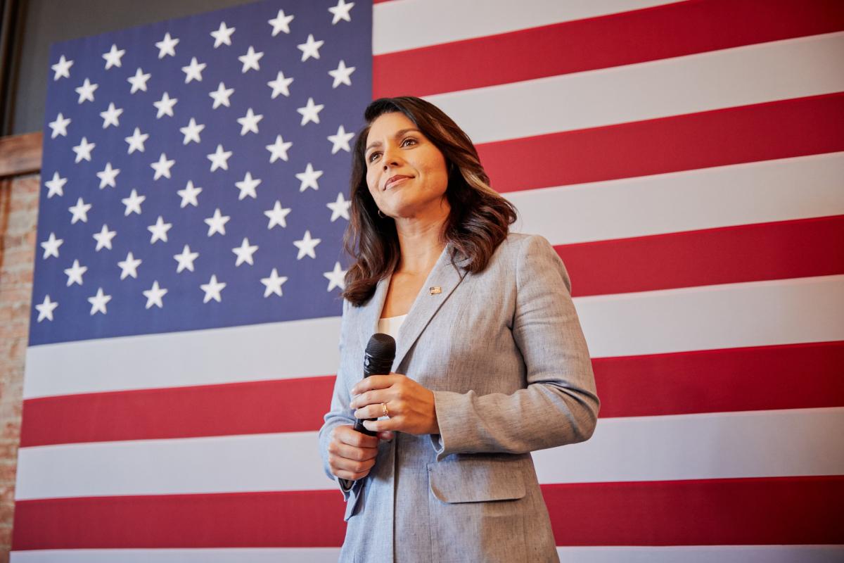 A photo of Tulsi in front of the American flag